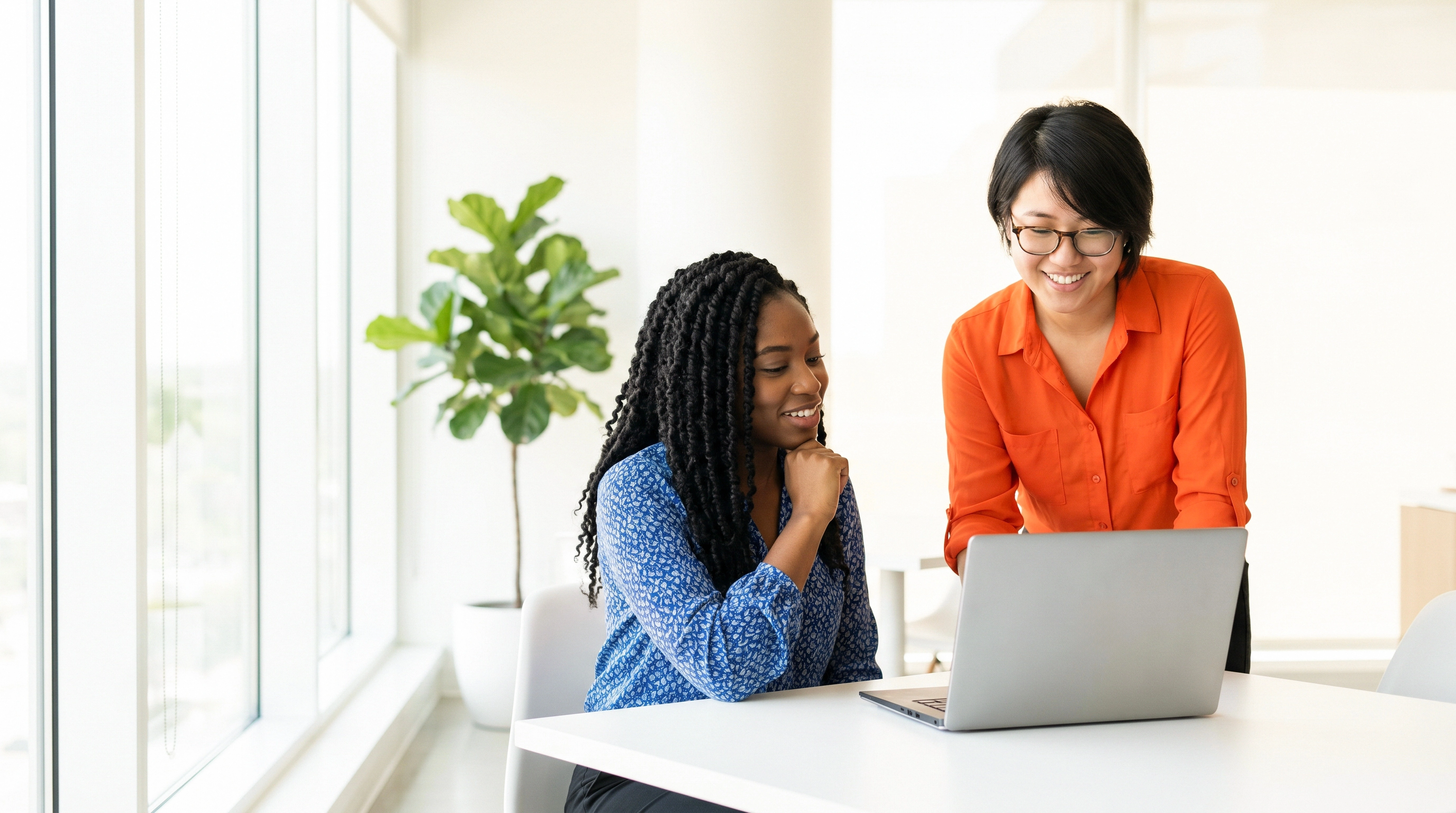 duas mulheres trabalhando com notebook em escritorio moderno