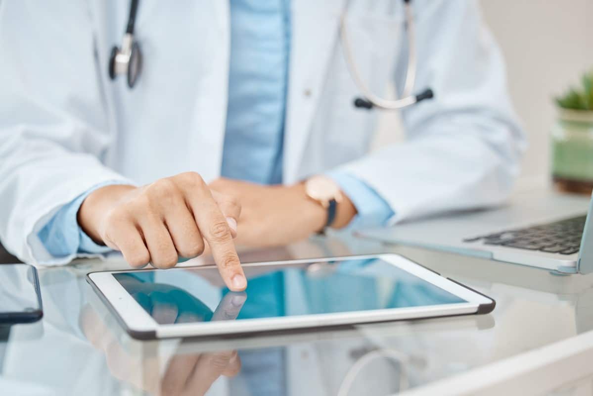 Médico de jaleco usa tablet na mesa, simbolizando o futuro na saúde digital com tecnologia e inovação nos cuidados médicos