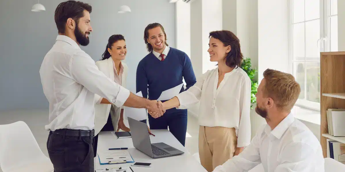 5 pessoas felizes finalizando uma reunião em uma mesa de trabalho para ilustrar um rh menos burocrático