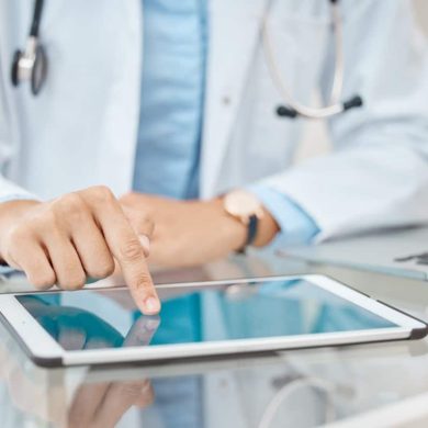 Médico de jaleco usa tablet na mesa, simbolizando o futuro na saúde digital com tecnologia e inovação nos cuidados médicos